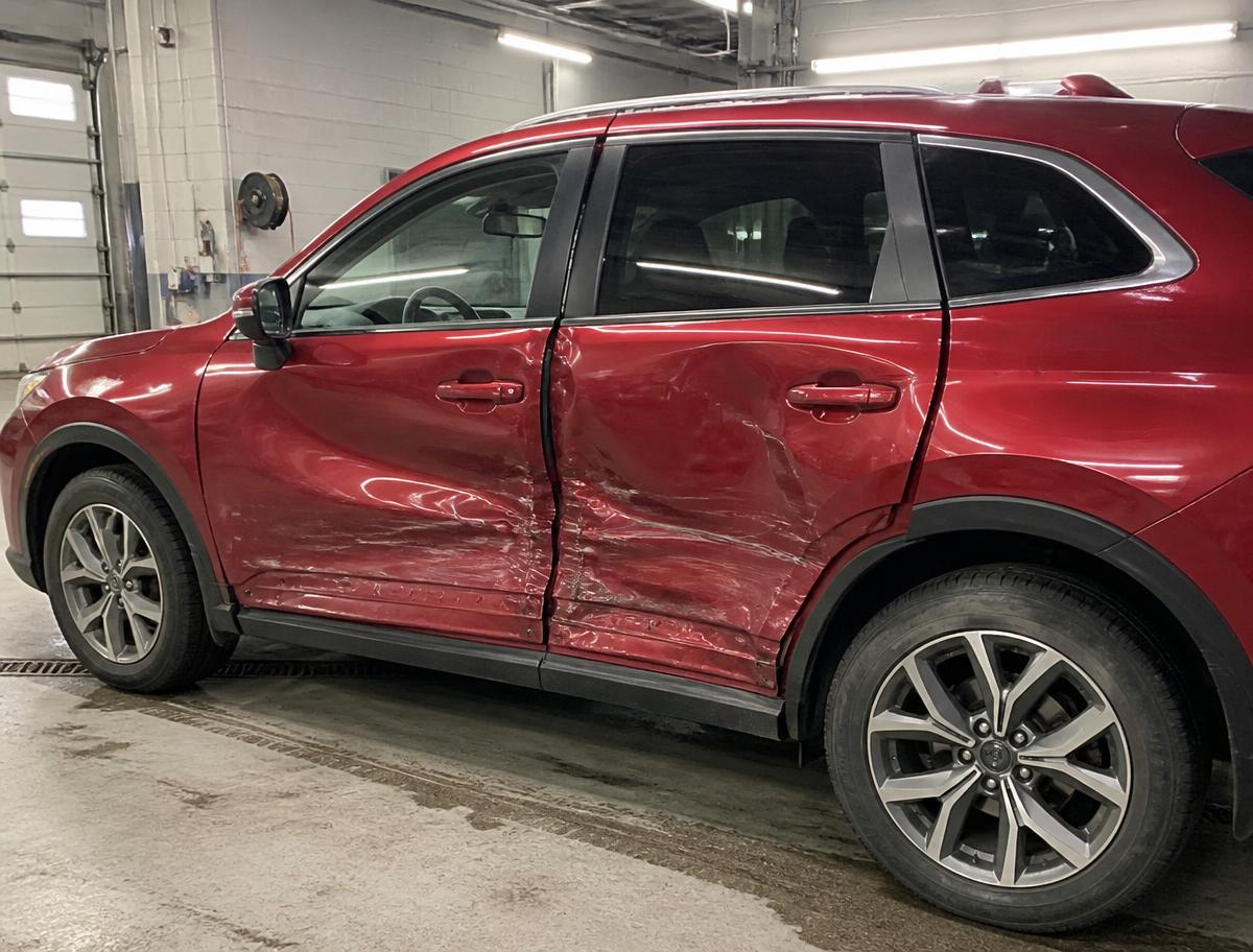 Red SUV with both driver side doors caved in and scraped after a side impact